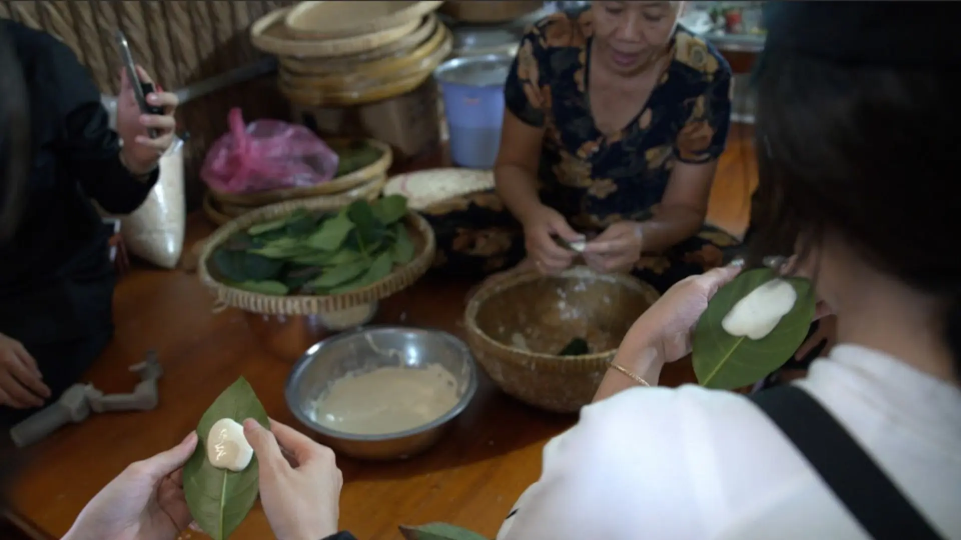 Người dân địa phương hướng dẫn khách làm bánh lá mít